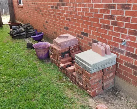 bricks, trash and logs piled up in a yard