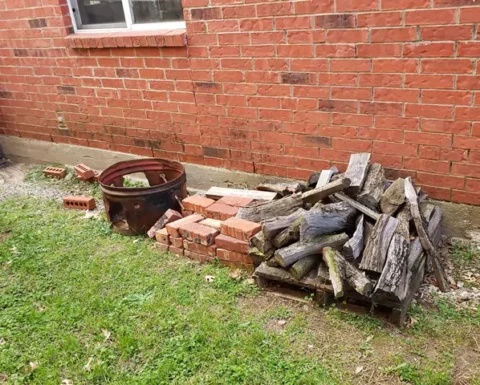 bricks, trash and logs piled up in a yard