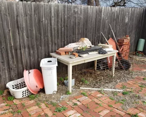 junk and old furniture and trash piled up in a back yard