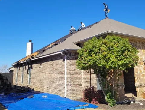 Pulling old shingles off a roof to replace with a new roof